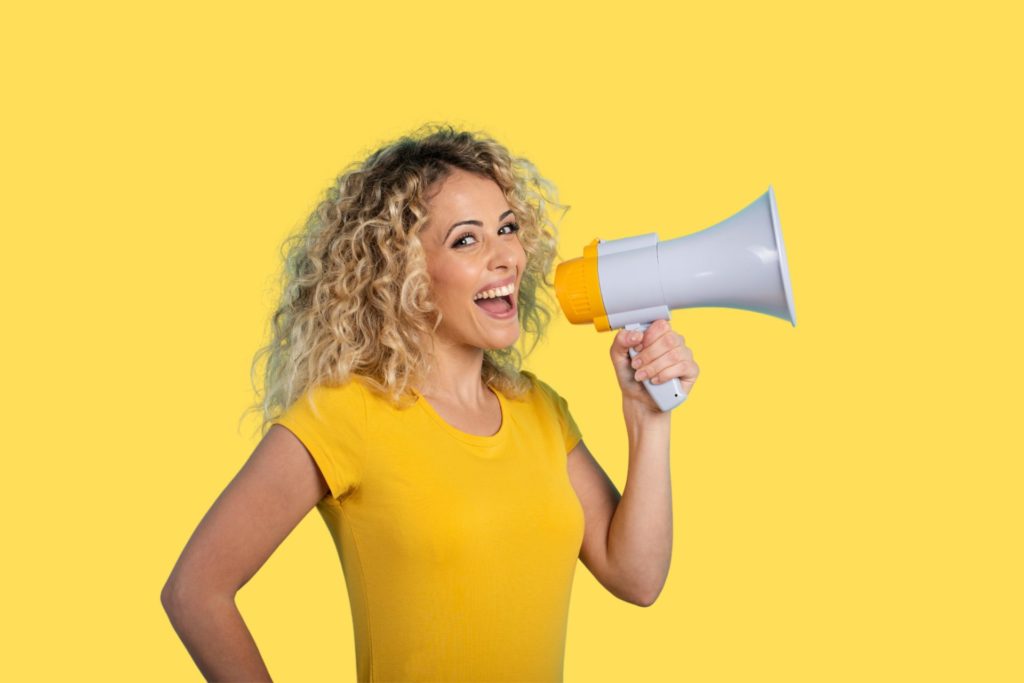 A woman smiling as she holds a megaphone