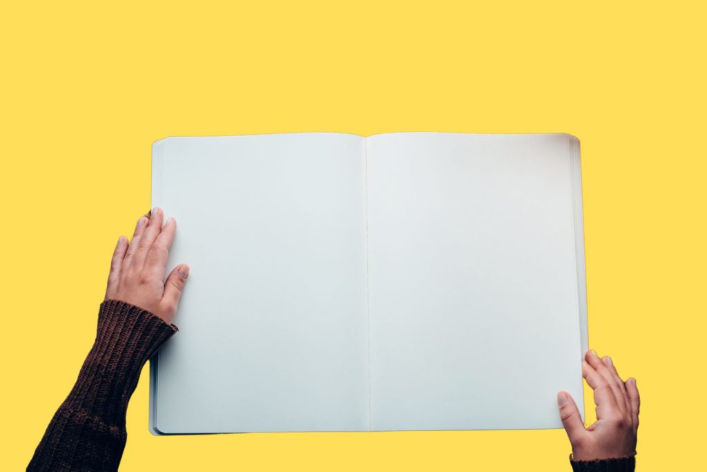 Two hands holding an empty-paged book