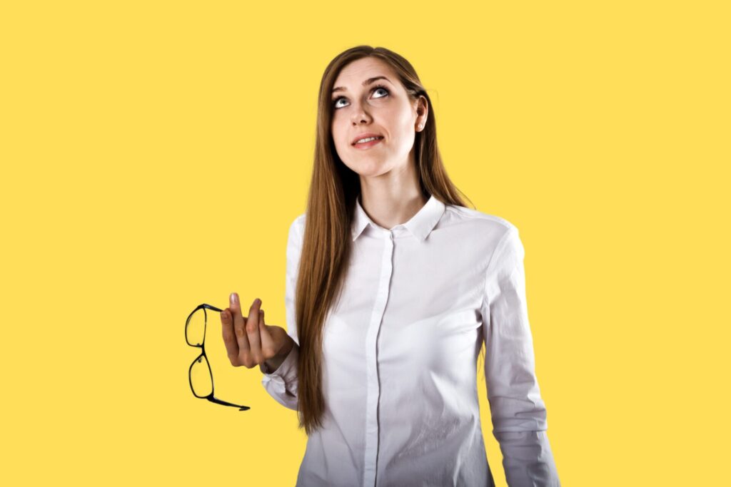 A woman holding glasses and looking upwards