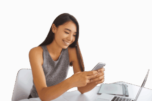 a smiling woman sitting t her desk and reading something on her phone