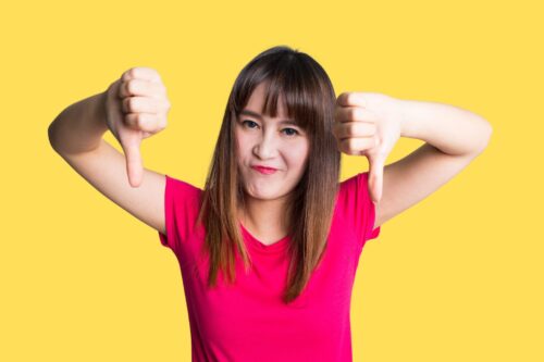 A person wearing a red shirt, with their two thumbs pointing downwards.